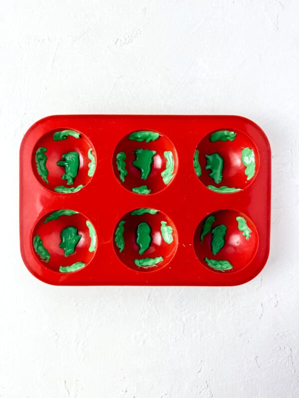 Silicone mold with green continents piped into the cavities.