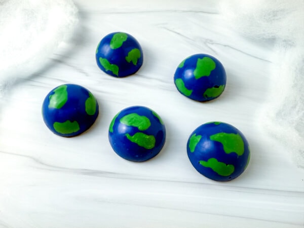 Five dome-shaped candies decorated to look like Earth.