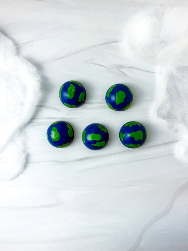Overhead view of five completed Earth chocolates surrounded by cotton clouds.