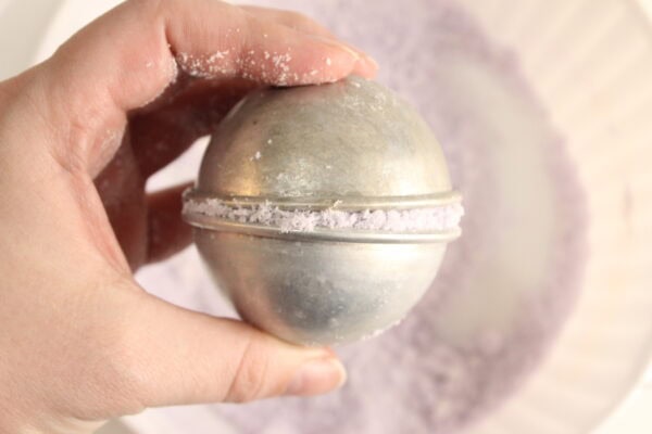 Hand holding a filled bath bomb mold.