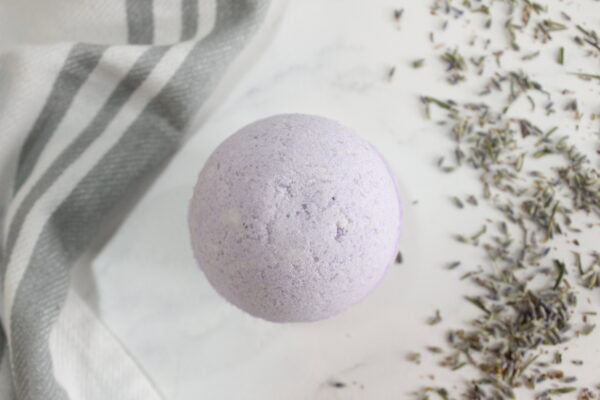 Top view of a purple bath bomb beside dried lavender.