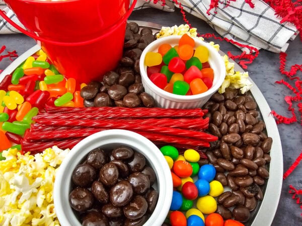 Side angle view of a colorful movie night charcuterie tray featuring chocolates, popcorn, licorice, and candy.