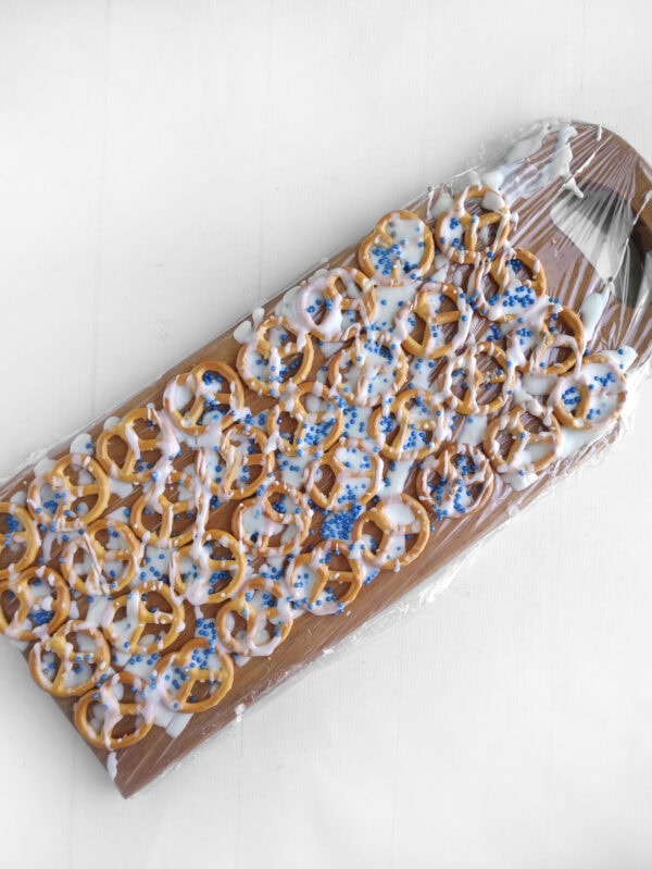 Pretzels on a tray drizzled with white icing and blue sprinkles.