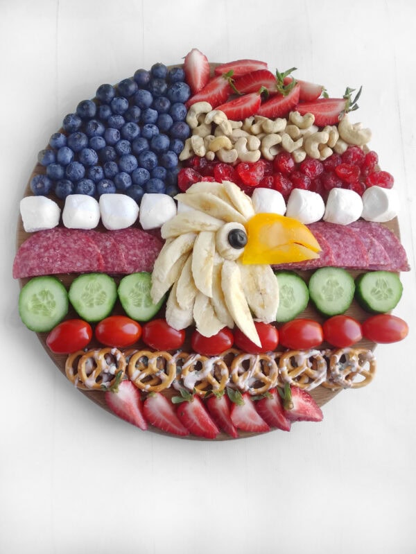 Completed charcuterie board with an eagle face made from fruit and snacks.