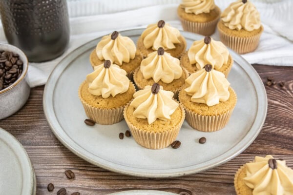 Plate of espresso cupcakes topped with piped frosting and coffee beans.