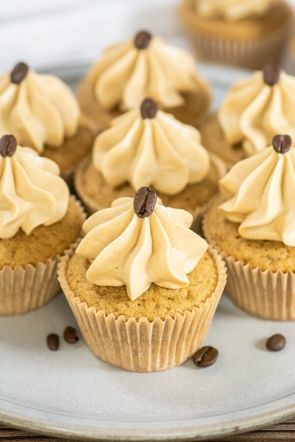 Close-up of espresso cupcakes with piped frosting and coffee beans.