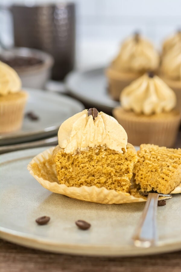 Espresso cupcake sliced in half to show moist texture, topped with frosting and a coffee bean.