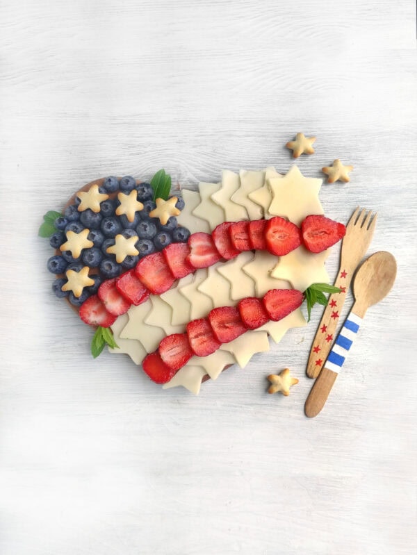 Final presentation of the heart-shaped patriotic charcuterie board with added decorative mint leaves and utensils.