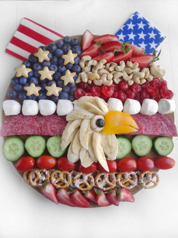 Final patriotic charcuterie board topped with fruits, snacks, and American flag decorations.