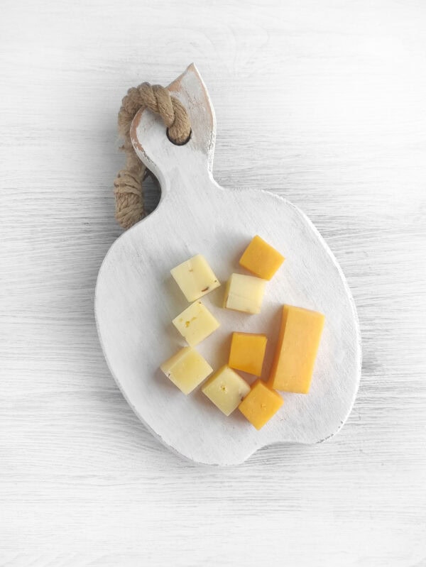 Assorted cheese cubes arranged on a small white serving board.