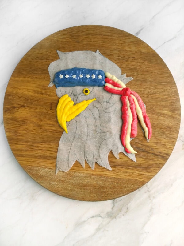 Eagle design outline on parchment with red, yellow, and blue frosting.