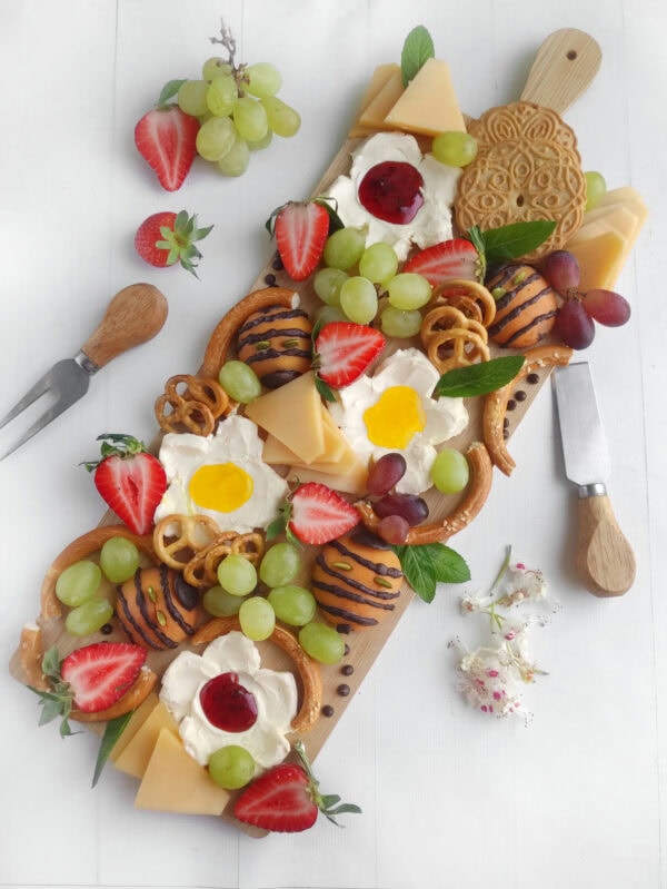 Decorated charcuterie board with fruits, cheese, and flowers styled for summer