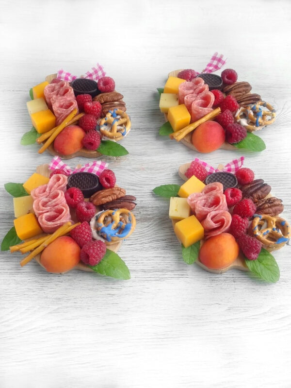Four assembled mini charcuterie boards on a white wood surface.
