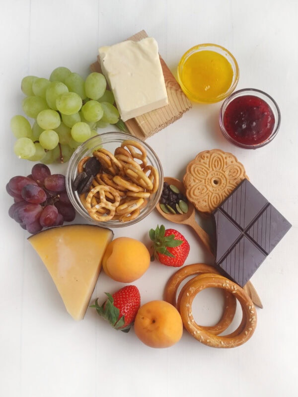 Ingredients laid out including grapes, cheese, pretzels, chocolate, cookies, and jam