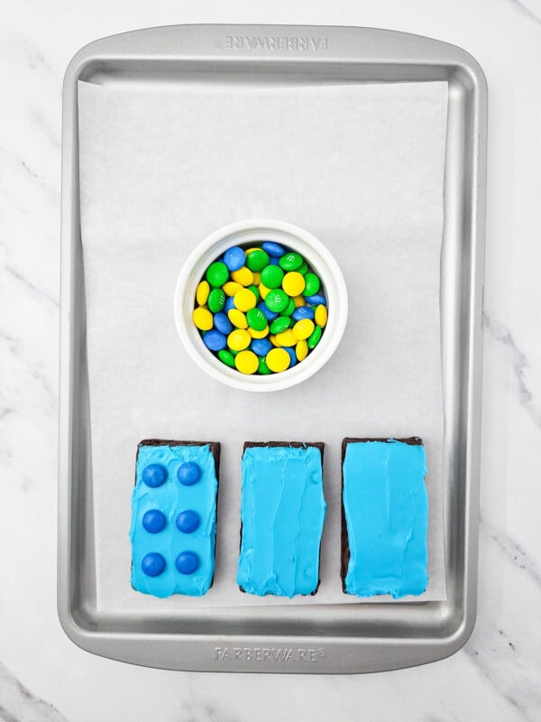 Blue frosted brownies with blue M&Ms added on top to create a LEGO brick effect