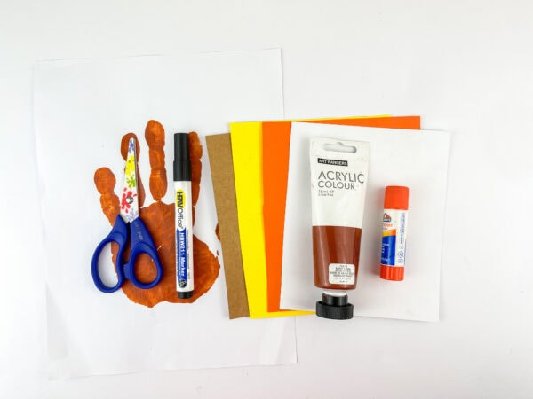Scissors, glue, paper, paint, and handprint shown as craft supplies