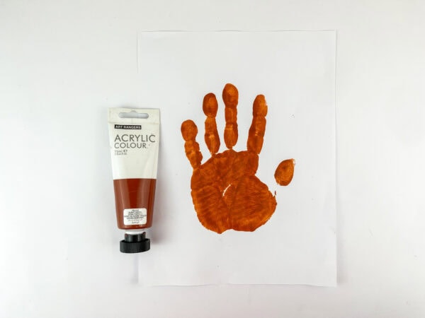 Orange handprint next to brown acrylic paint on white paper