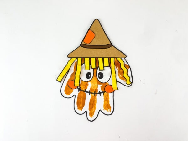 Completed handprint scarecrow with face, hair, and hat on white background