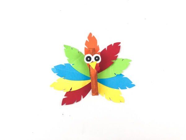 Finished turkey clothespin craft with colorful paper feathers.