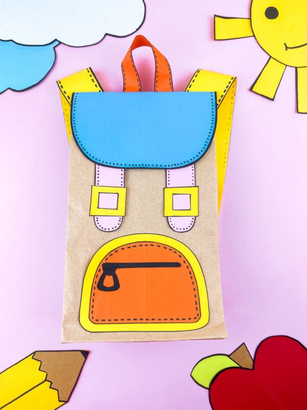 Completed paper bag backpack surrounded by cutout sun and clouds