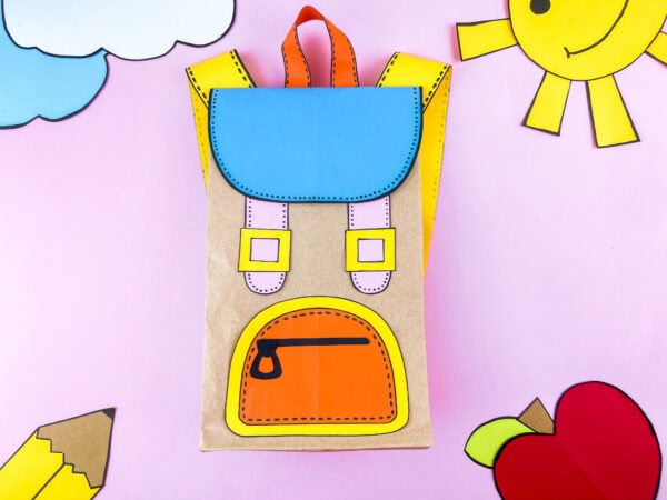 Paper bag backpack craft displayed flat with colorful cutouts