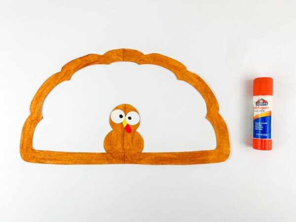 Turkey face glued on orange paper outline.