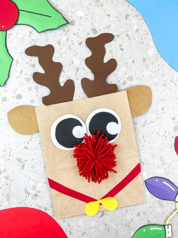 Close-up of reindeer paper bag craft with pompom nose and big eyes.