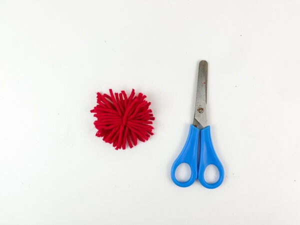 Red yarn pom-pom with scissors
