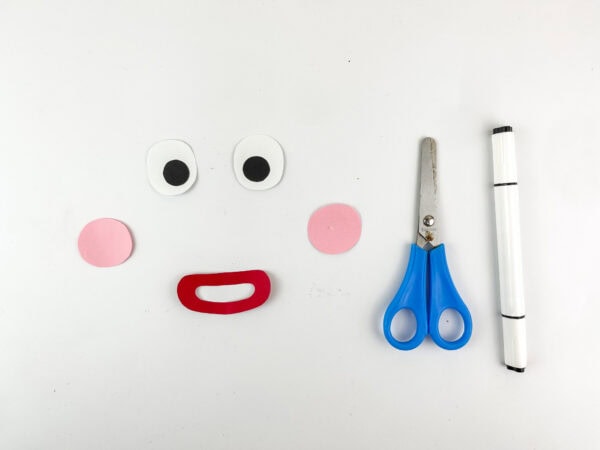 Cutout gingerbread face parts including eyes, cheeks, and mouth with scissors