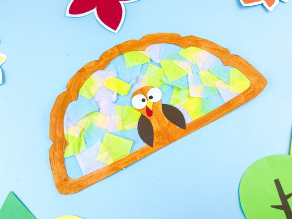 Turkey suncatcher craft with orange border and tissue paper feathers.