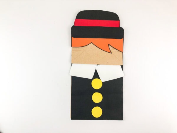 Paper bag puppet with attached hat and hair.