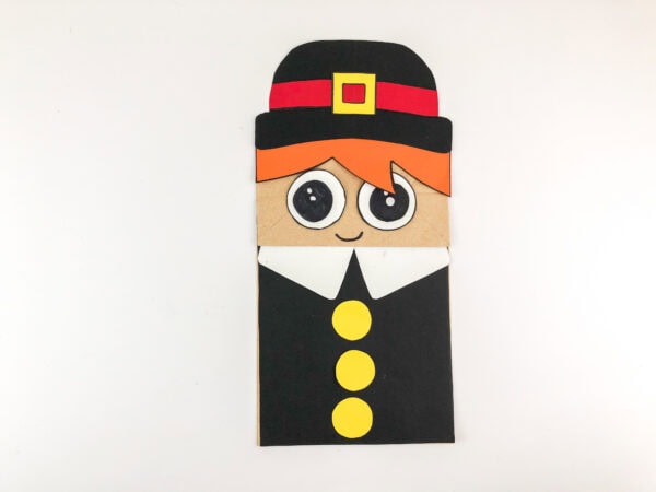 Completed pilgrim puppet with eyes, collar, buttons, and belt buckle.