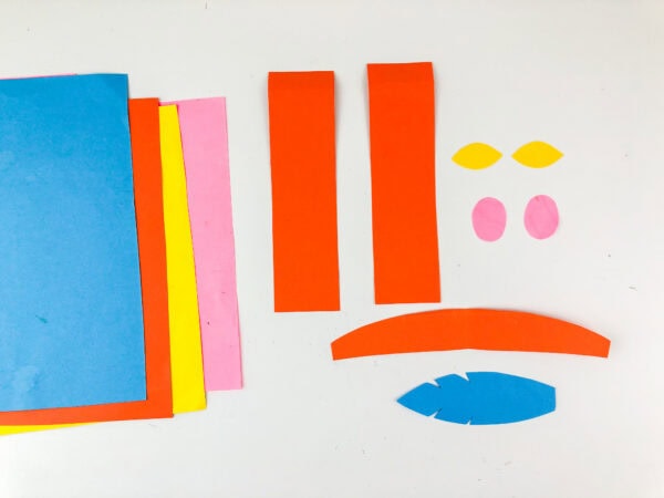Colored paper sheets with clothing, feather, and facial pieces.