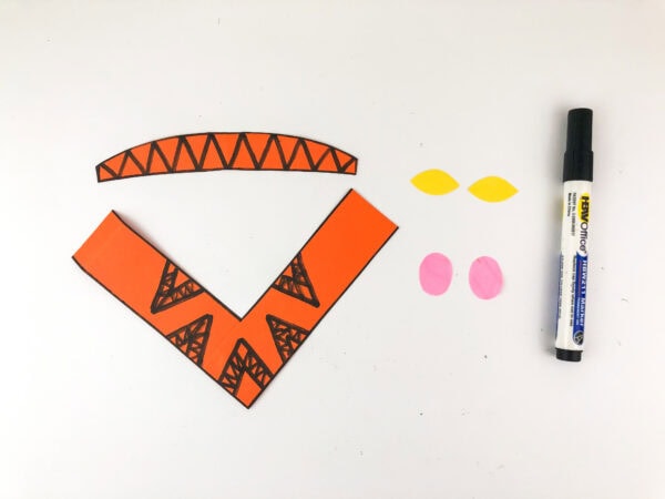 Orange paper clothing with drawn patterns and extra cutouts.