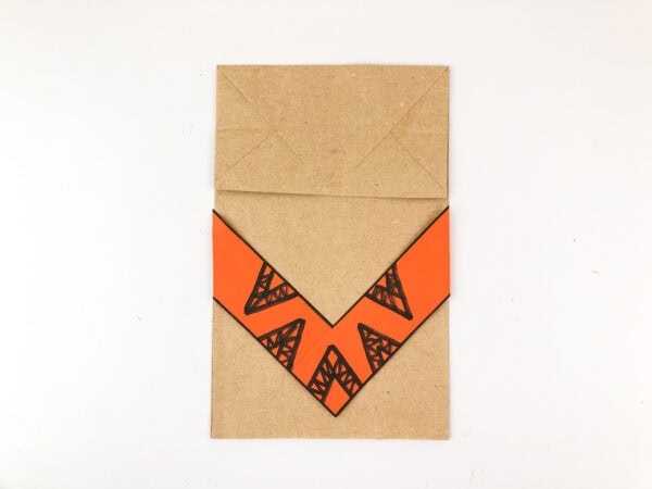 Orange patterned clothing glued to paper bag base.