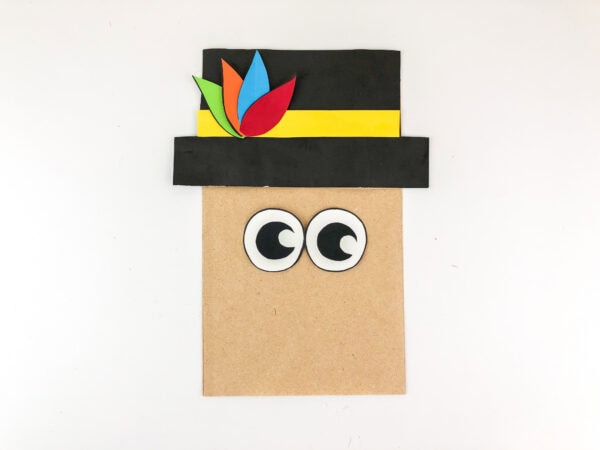 Paper bag with pilgrim hat and attached cartoon-style eyes.