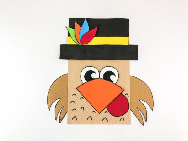 Pilgrim turkey paper bag craft with black hat and orange beak.