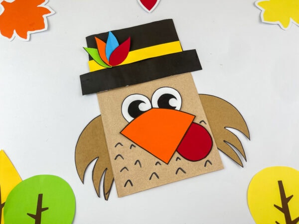 Angled view of pilgrim turkey paper bag craft with autumn decorations.