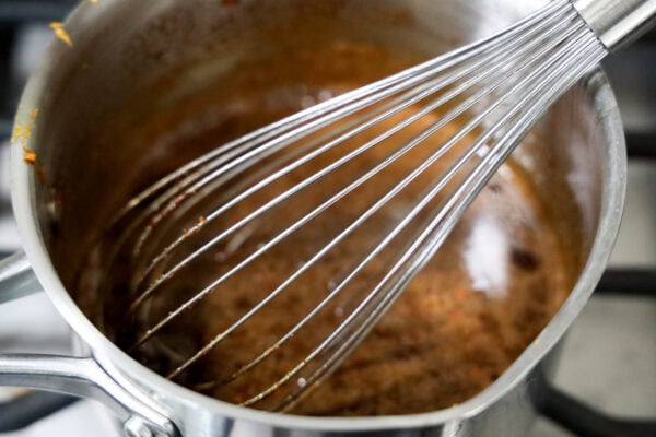 Whisk mixing spiced molasses in saucepan