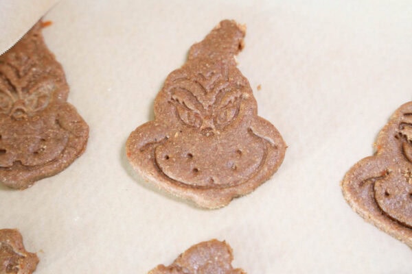 Grinch-shaped cookie dough on parchment paper
