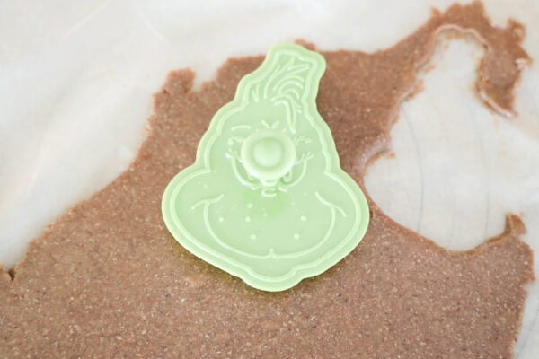 Grinch cookie cutter pressed into rolled dough