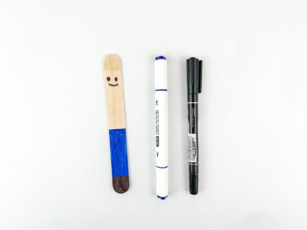 Popsicle stick colored with blue pants, brown shoes, and smiling face.