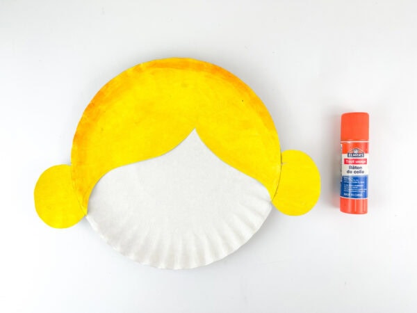 Yellow hair pieces glued onto a paper plate face.