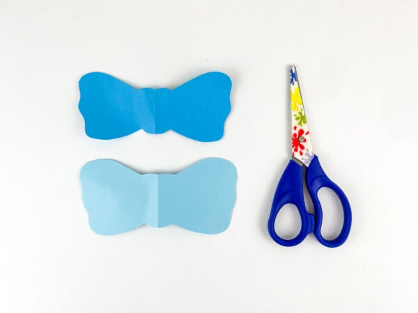 Two blue paper bow shapes beside scissors.