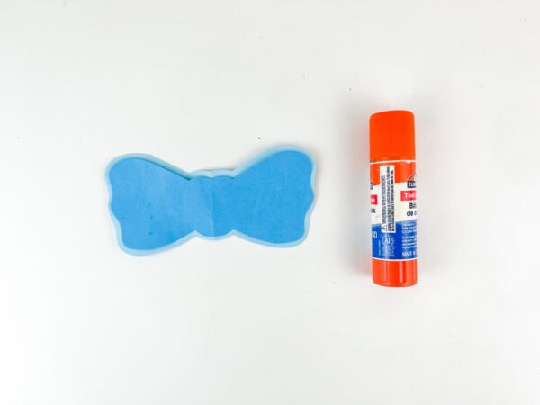 Blue paper bow assembled beside glue stick.