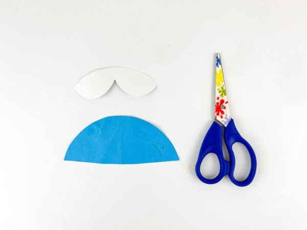 Blue semicircle and white collar paper pieces beside scissors.