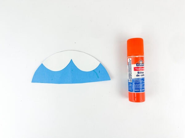 Blue and white paper collar assembled beside glue stick.