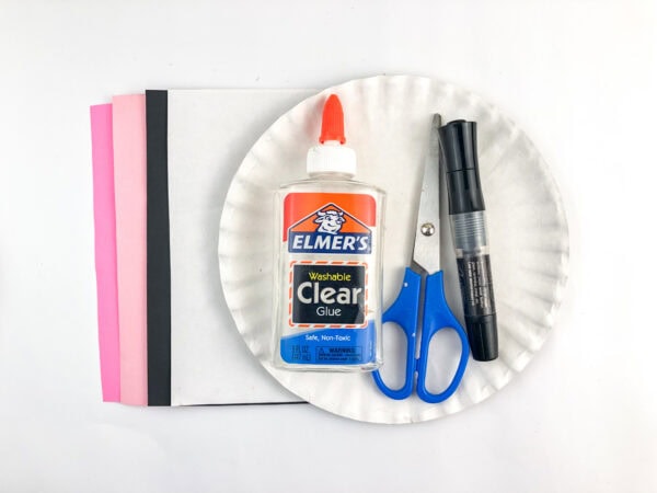 Craft supplies including paper plate, glue, scissors, markers, and colored paper.