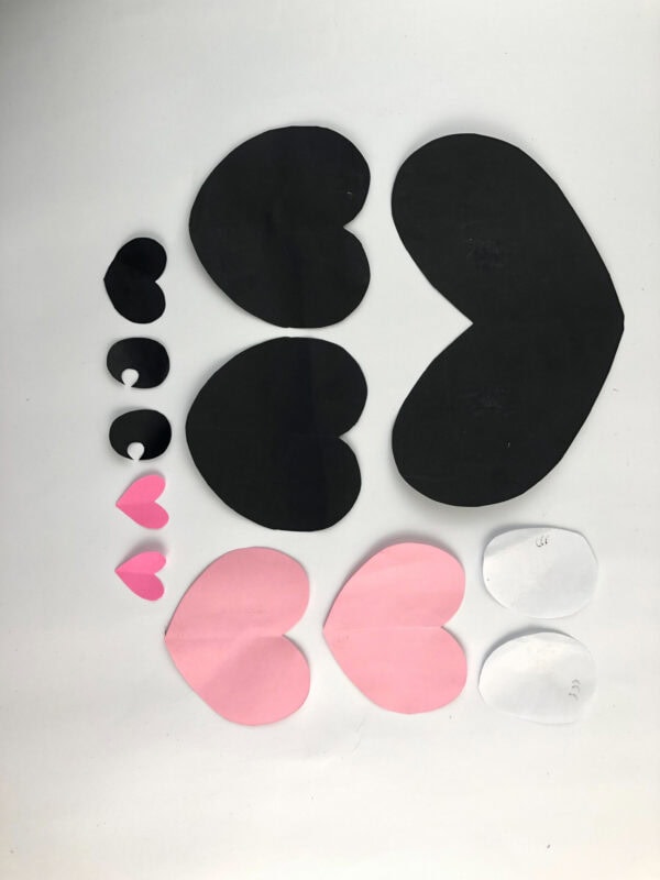 Cut-out paper shapes for panda craft laid out in rows.