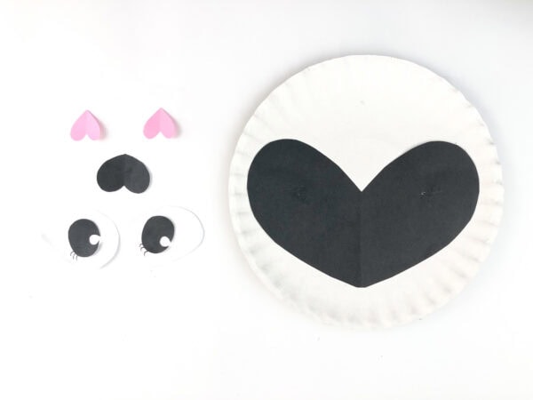 Panda face pieces placed beside a paper plate with black mask.